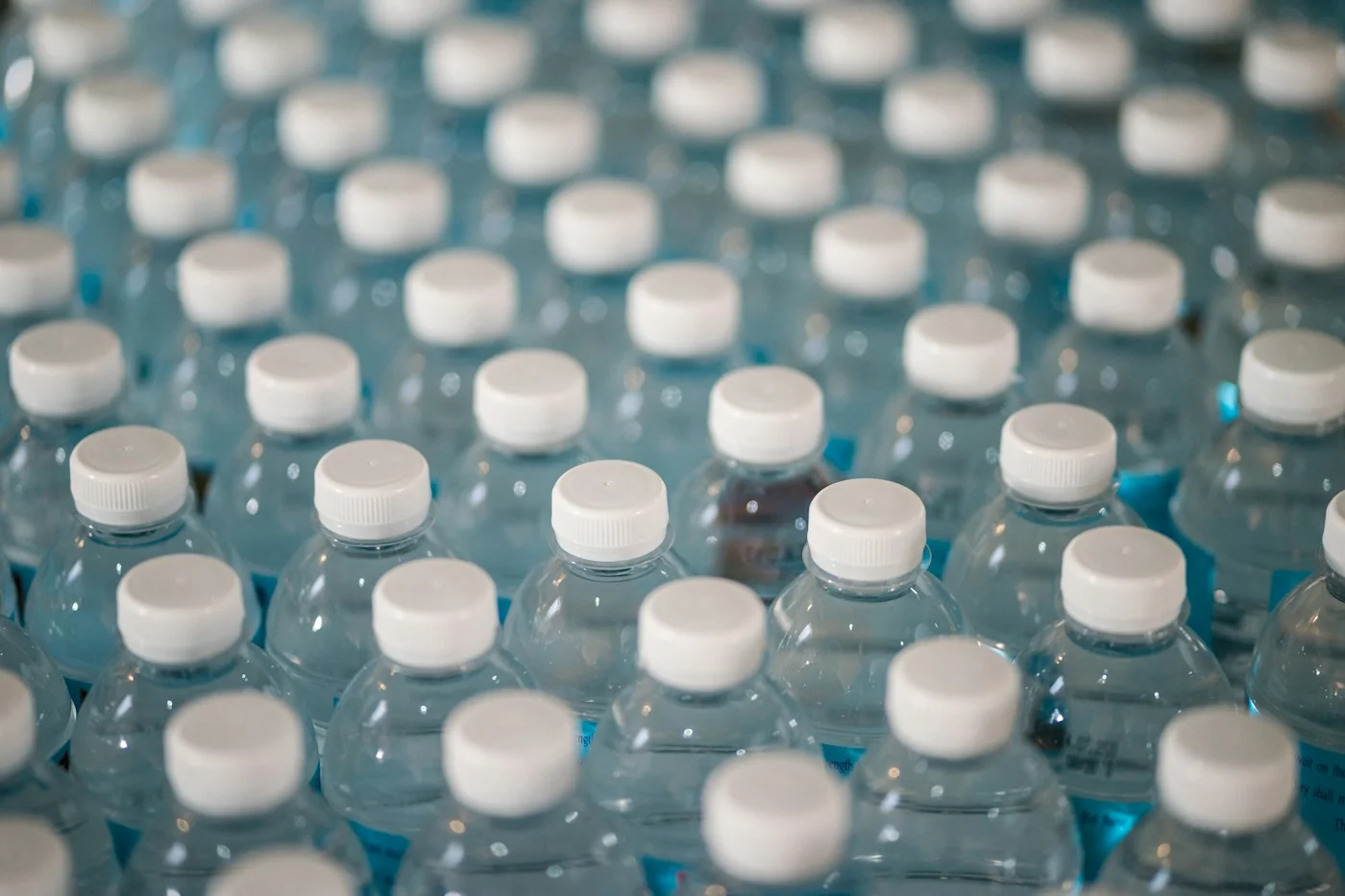 Rows of clear bottled water with white caps.