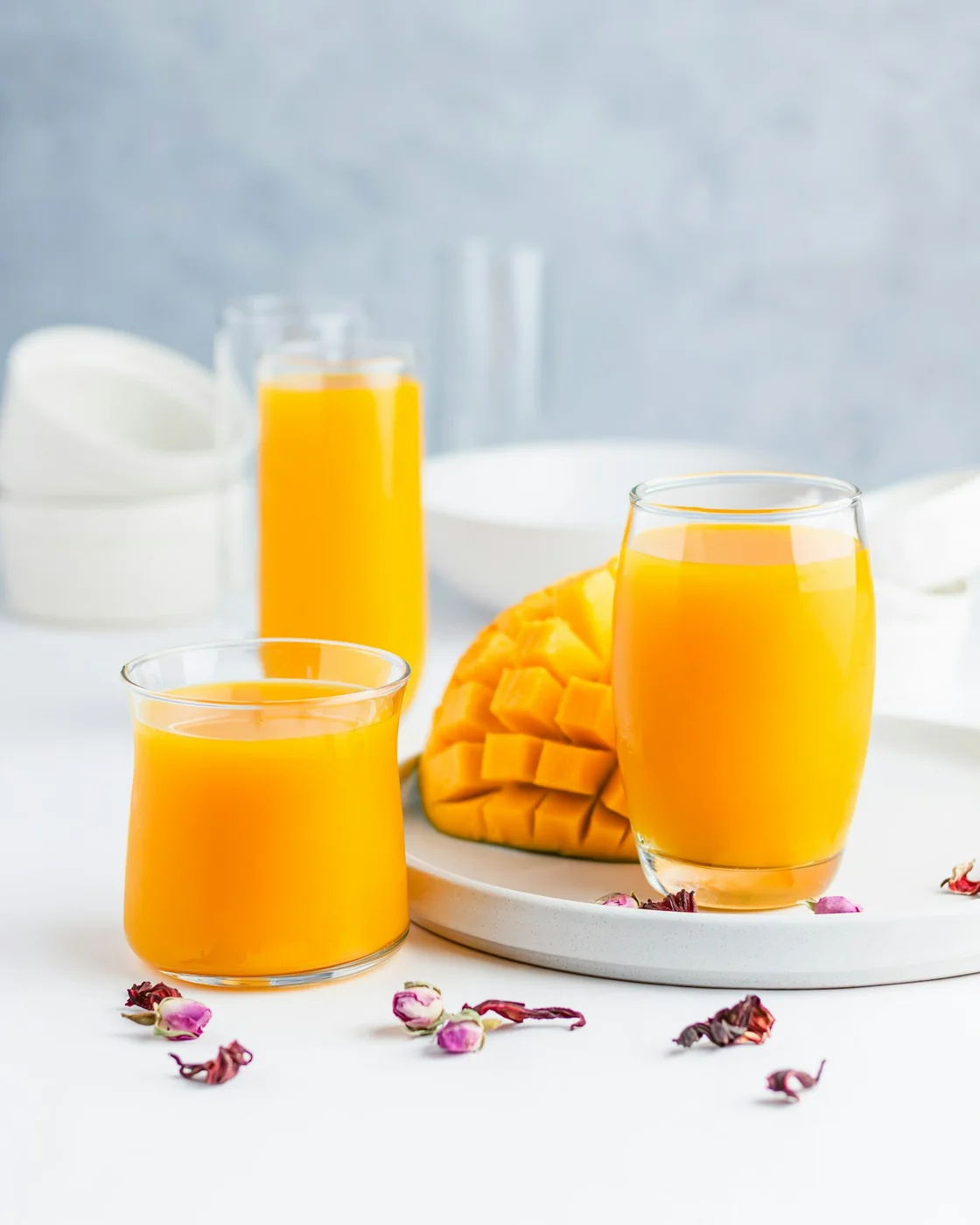 Golden mango juice served beside a freshly cut mango.